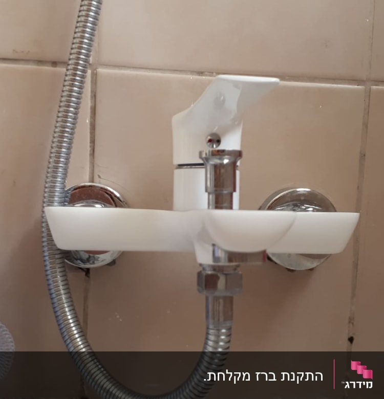 ברז מים עם צינור מתכת בחדר אמבטיה